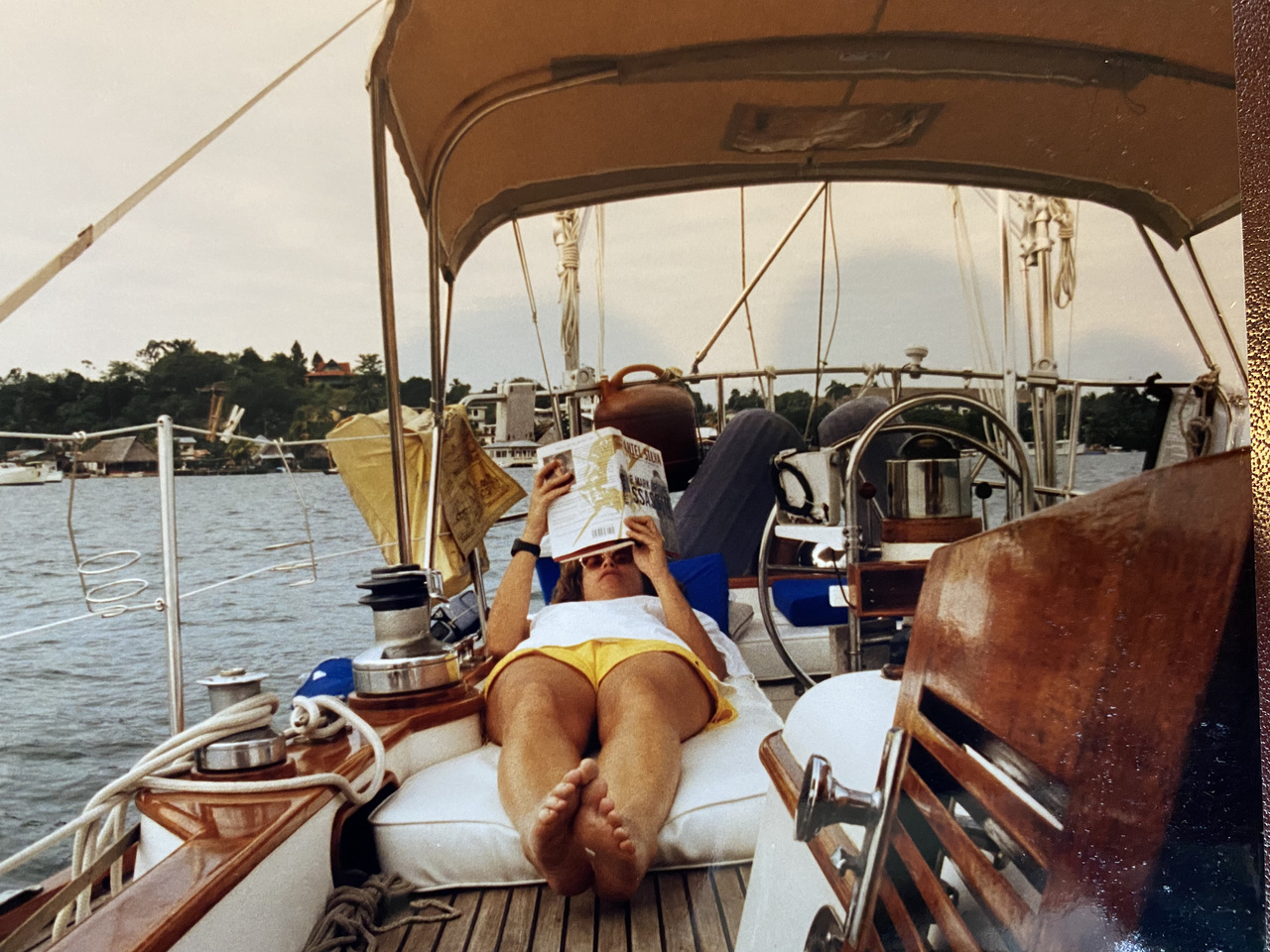 Susan Cole lying on a sailboat and reading.